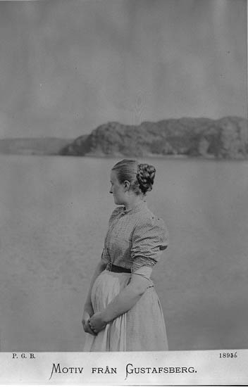 En kvinna står och blickar ut över vattnet i Gustafsberg. Kvinnan håller armarna runt sin mage och är troligen gravid.