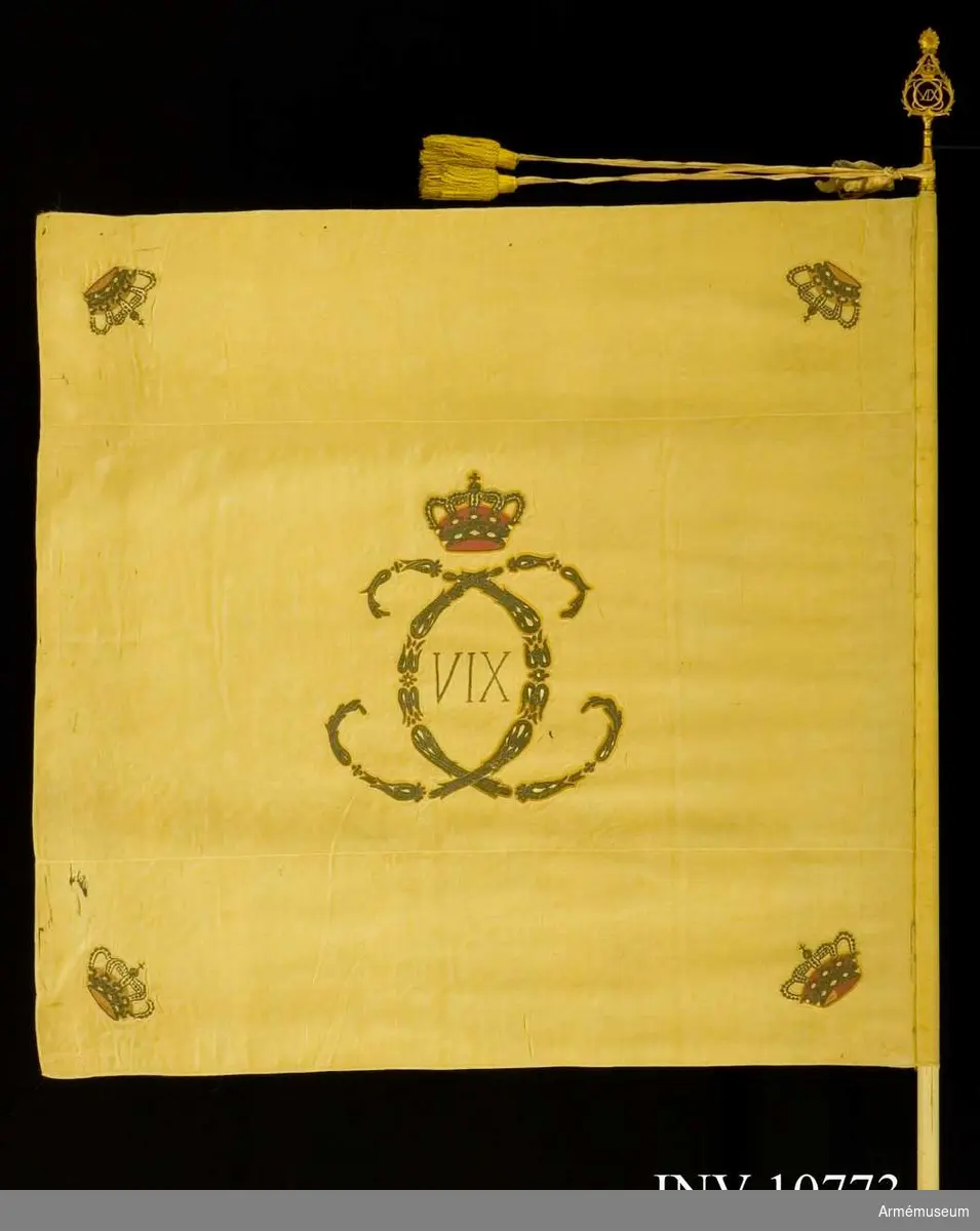 Broderad med silver. Samhörande: Kravatt, vitt siden, 160 cm lång plus tofsar 14 cm. Fanspets med Karl XIV Johans namnchiffer.