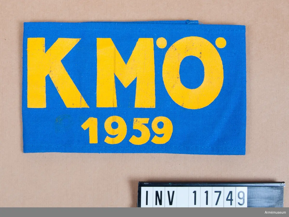 Grupp C I.
Armbindel med beteckning  "KMÖ 1959". Armbindeln utdelad till inbjudna åskådare vid Krigsmaktövningar 1959 i Östergötland av Försvarsstaben.
Gåva från rikshemvärnschefen generalmajor Per Kellin.