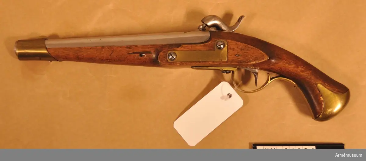Grupp E III c.
Tappstudsarpistol med slaglås, reparationsmodell.
På kammarstycket tre kronor och på snäckan en krona. Pistolen har beslag för löskolv. (Pistolen är exakt lika  AM 34822, vilken uppges vara m/1820-1857).