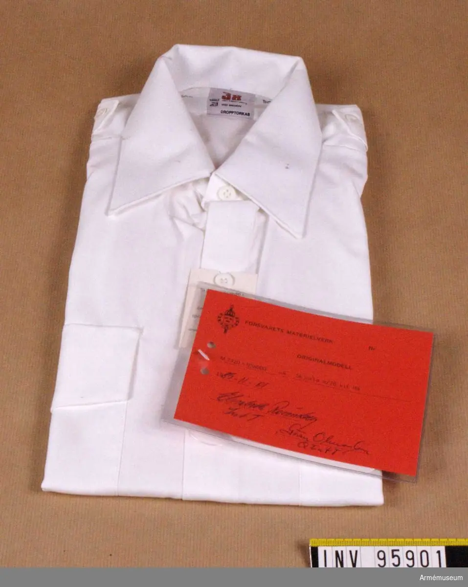 Skjorta med hel, fast krage och ok av dubbelt tyg. Skjortan har bröstfickor med lock som knäpps. Fasta axelklaffar, bredd 42-45 mm, utan axelklaffshylsor. Kort ärm. Skjortan är avsedd för alla uniformsdräkter inom försvaret där vit skjorta är tillåten.
Vidhängande etikett: "Försvarets materielverk Originalmodell M 7320-056000-4, Skjorta m/78 vit HÄ, 1985-11-01 Elisabeth Rönnberg Int T / Göran Olmarker Q Int T".