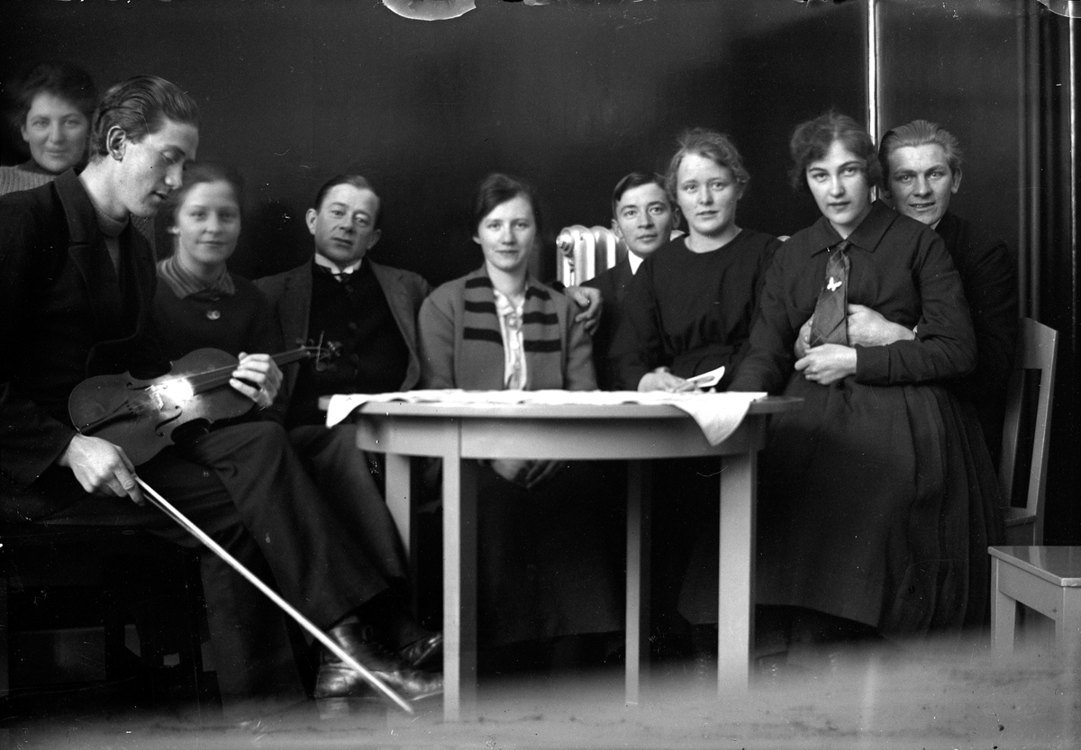 Fem kvinnor och två män, varav en håller en fiol, sitter vid ett bord.   Lungkliniken i Eksjö.