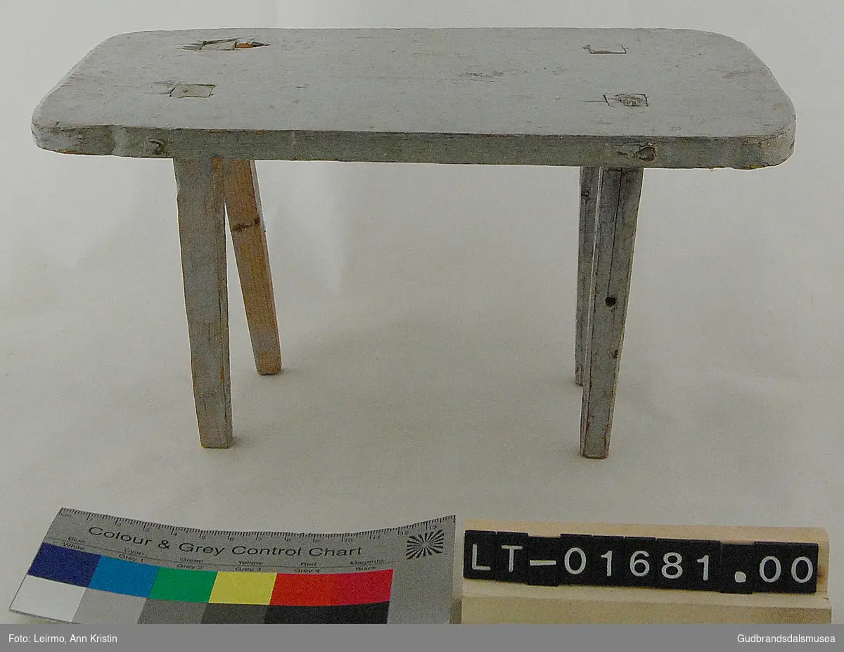 Lite rektangulært dukkebord med fire bordbein felt inn i bordplaten.