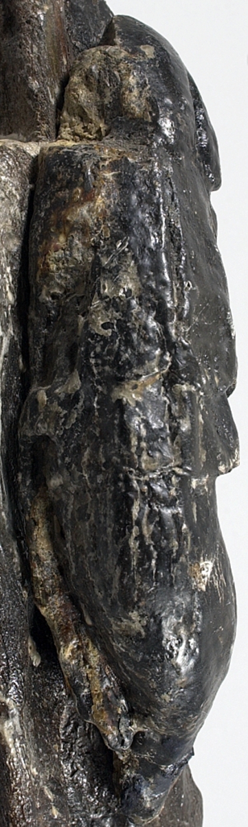 Kejsare. Skulptur föreställande en mansfigur med lagerkrönt huvud och slätrakat ansikte. Figuren är iförd romersk rustning - troligtvis av thoraxmodell - med mantel. Manteln är draperad i rika veck över bröst och mage och hopfäst på höger axel.
Figurens kropp är frontalt riktad, med huvudet vridet något mot vänster. Kroppen stöder på vänster ben medan höger ben hålls böjt och något fört åt sidan. Upptill är bakstycket framdraget i en "huvudplatta".



Figuren står på en sockel, vilken pryds av en maskaron. Maskaronen har stora, stirrande ögon, platt och bred näsa samt grinande mun. Under maskaronens mun är en namnbanderoll placerad. Dess vänstra del upptar ett A, föregånget av en bokstav som kan tolkas som ett C eller G. Efter A:et följer ett litet ornament, placerat rakt under maskaronens mun, varefter kommer bokstaven L. Resterande bosktäver är helt utplånade.



Skulpturens baksida är rak och uppvisar tre snedställda, olika djupt liggande fält. De tre fälten, som utgör anliggningsytor, ger skulpturen en trappstegsformad profil.

Skulpturen är relativt välbevarad, förutom figurens ansikte som är mycket slitet. Båda armarna är bortbrutna, en arm är funnen separat, men det är osäkert om det är höger eller vänster arm. Vidhängande delar av mantelns vänstra sida är fastskruvad. Stora partier av huvudplattan saknas. Maskaronen på sockeln är sprucken och ett parti på vänster sida saknas.



Text in English: Sculpture representing a male figure with laurel-wreathed head and a clean-shaven face. The figure is wearing thorax armour with the mantle richly folded over the chest and stomach and fastened at the right shoulder.



The figure''s head inclines slightly to the left while the body faces forward. The body rests on the left leg, while the right is slightly bent.

The upper part of the back extends upwards in a "head board".



The figure stands on a plinth decorated with a mask. The mask has large, staring eyes, flat broad nose and grimacing mouth. Beneath the mask there is a name inscribed: beginning with either CA or GA, after the A there appears to be a small ornament which is followed by the letter L. The remaining letters are indecipherable.



The sculpture''s back has three obliquely placed flat surfaces of different depths, that are areas of attachment. The flat surfaces make the sculpture look like a step-ladder in profile.

The sculpture is rather well preserved apart from the face which is very damaged. The figure''s arms are broken off. One arm was found separately, but it is not clear whether it is the left or right arm. Parts of the mantle and the board over itÂ´s head are missing.