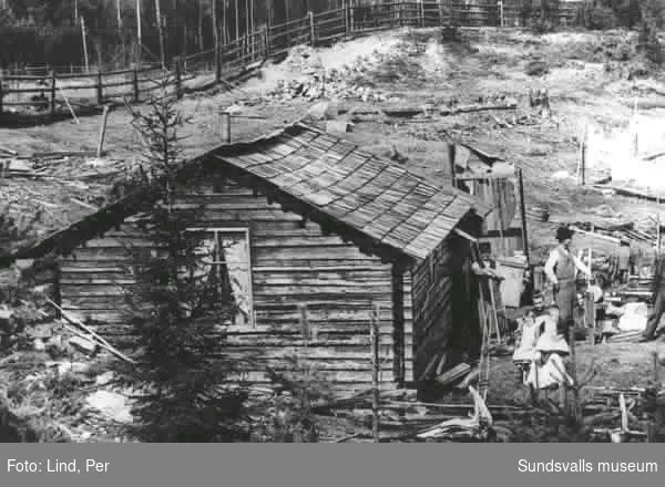 Alby 1898. Arbetarbostad. Kvinna med två barn samt två män i bakgrunden.
