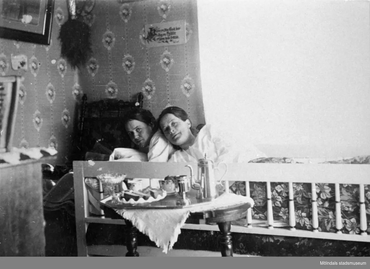 Valdeborg Johansson ligger i sängen bredvid en kvinnlig seminariekamrat, när Valdeborg gjorde sin lärareutbildning, 1910-tal. Ur Valdeborg Johanssons fotoalbum.