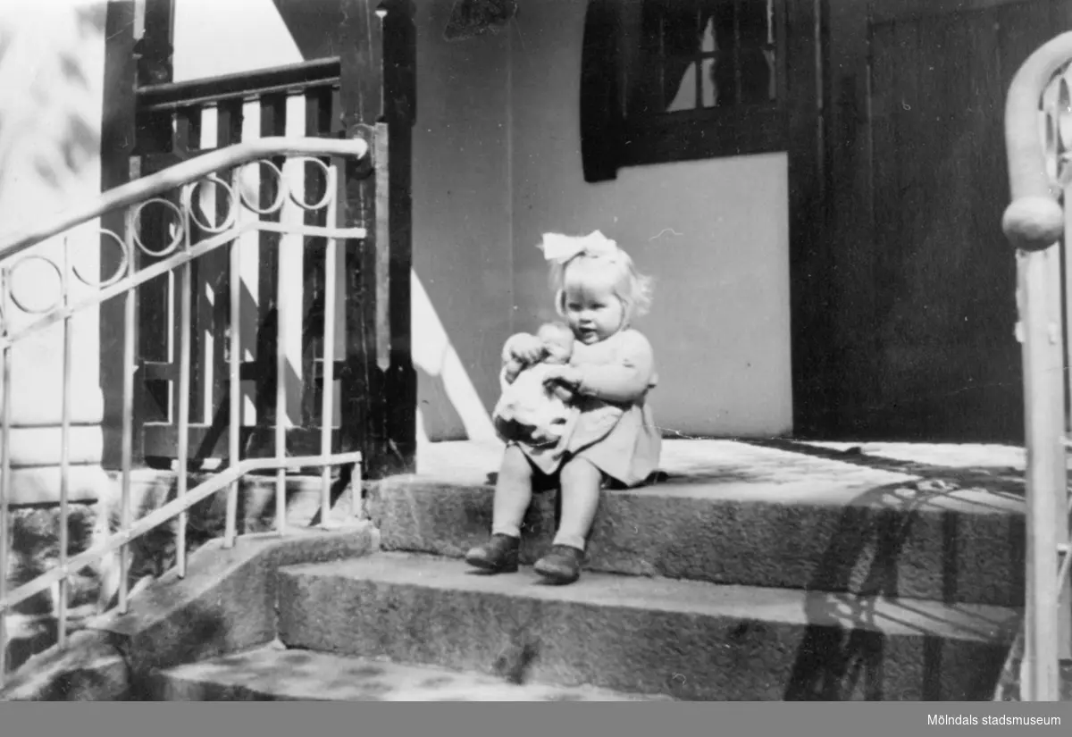 Inga-Lill Lipovsék, 4 år, sitter på en trappveranda med en docka i famnen, 1951. Hon bodde på Stretereds vårdhem från två års ålder.