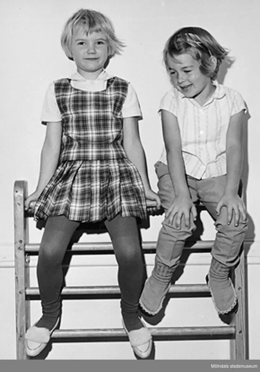 Två flickor sitter högst upp på en ribbstege vid Holtermanska daghemmet 1953.