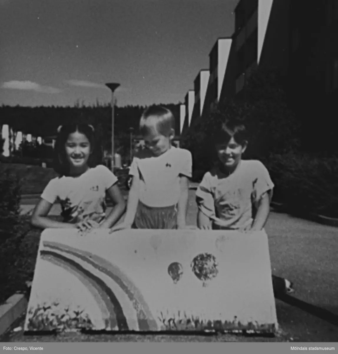 De tre barnen Dos-Alva, Helena och Carita, boende i bostadsrättsföreningen Tegen, som målade "suggorna" (väghindren) på föreningens område i början av 1980-talet. Barnen är namngivna från vänster.