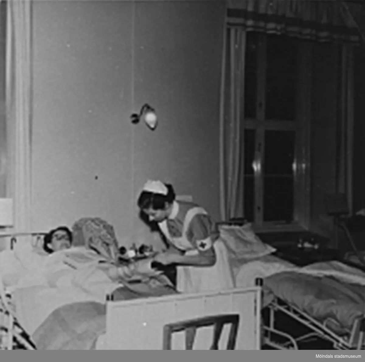 En sköterska tar hand om en patient på Sabbatsbergs sjukhus i Stockholm, cirka 1958. Det var viktigt att ha uppkavlade ärmar vid beröring av patient.
