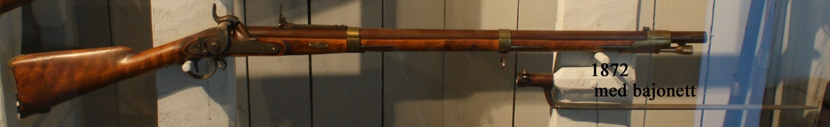 Gevär, 1815 - 1845 - 1848 års reparationsmodell, s.k. tappgevär, slaglås (Tischgevär). Märkt: Tre kronor. Kolven av trä, pipa och mekanism av stål. Beslagen av metall. Pipan räfflad.