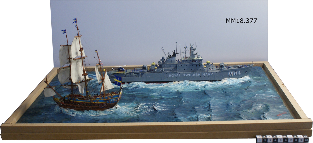 Fartygsdiorama bestående av två fartyg som passerar varandra: skeppet Karlskrona och minfartyget Carlskrona. Skeppet Karlskrona har tre master med satta segel, dubbla batteridäck, hög akter med fönster till överkajutan, akterspegeldekor bestående av stora riksvapnet, i fören krönt galjonsbild. Örlogsflaggor i masttopparna. Brunt skrov, överbyggnaden blå och gul. Minfartyget Carlskrona är grått, försett med helikopterplatta på akterdäck. Namn på båda sidor om fören "M 04 CARLSKRONA" samt "ROYAL SWEDISH NAVY" (Denna benämning realiserades aldrig ). På fartyget finns små figurer på däck och i master. Fartygen är placerade på rektangulär platta i ett hav av plastelina i gröna toner, signerad i ena hörnet i rött: " H.Biärsjö ". Försedd med glashuv med text: " 1680 Karlskronavarvet  1980 300 år ".