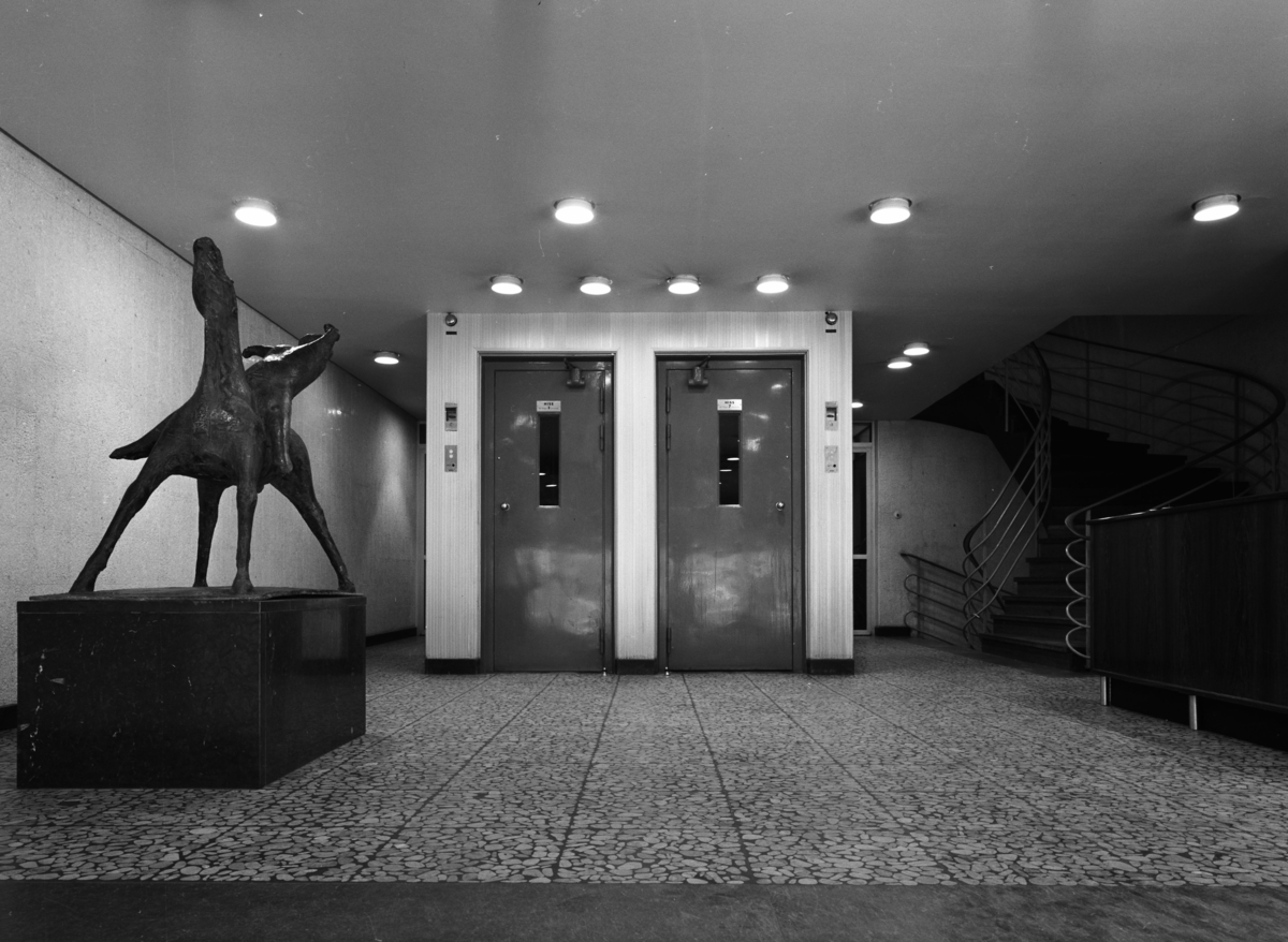 SIF - huset
Interiör av entrén med skulptur. Tända spotlights i taket framför hissdörrar