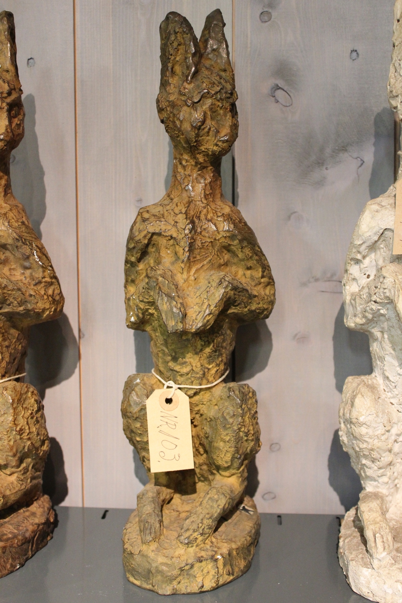 En skulptur i bronse av en hare sittende på to. Se også nr. 102 og nr. 104.