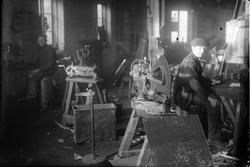 Bilde av arbeidere og maskiner på et verksted.