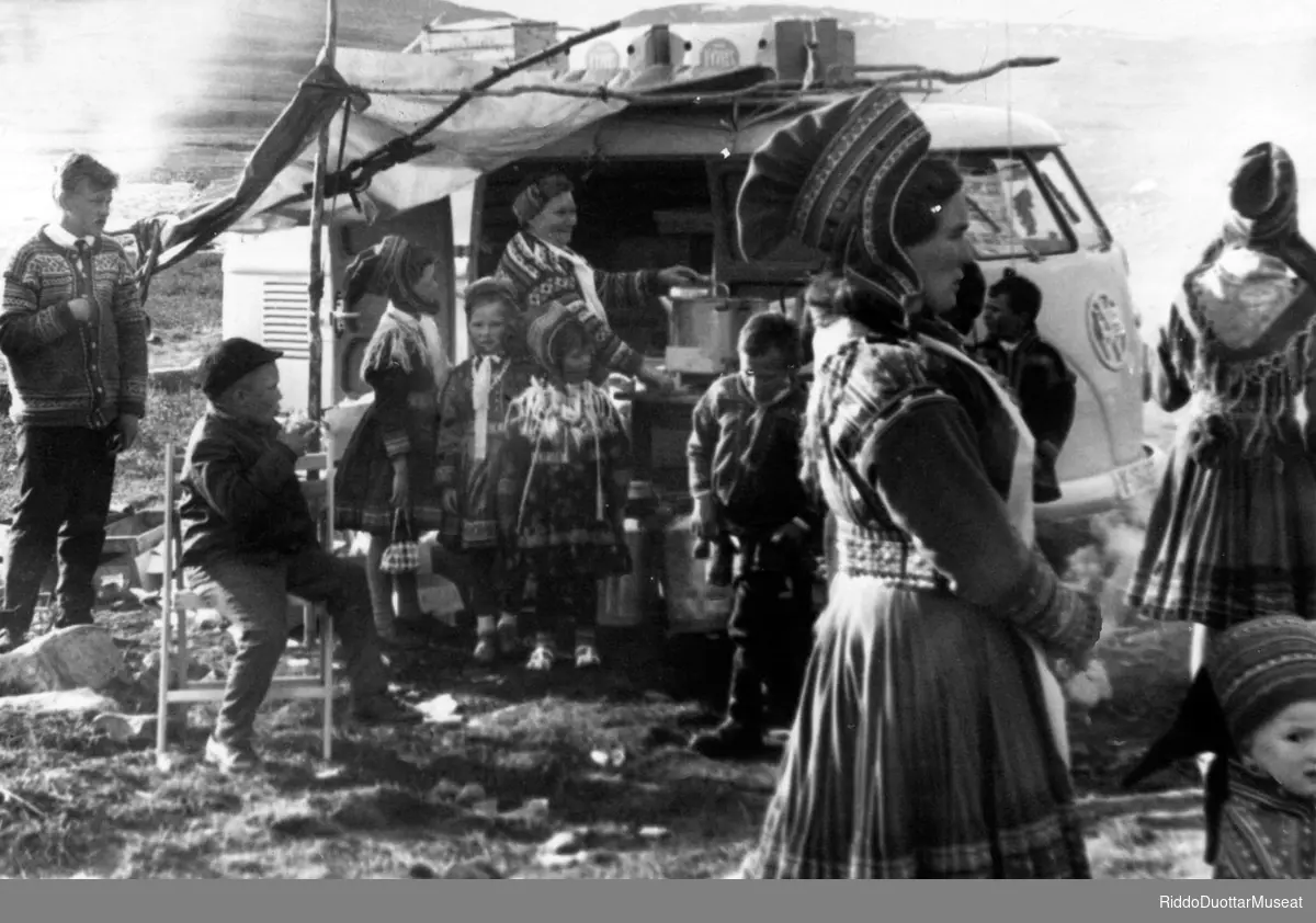 Olbmot biila guoras, sámimišuvnna steavnnat Áisaroaivvis.
Mennesker står utenfor en bil, stevne på Sennalandet.