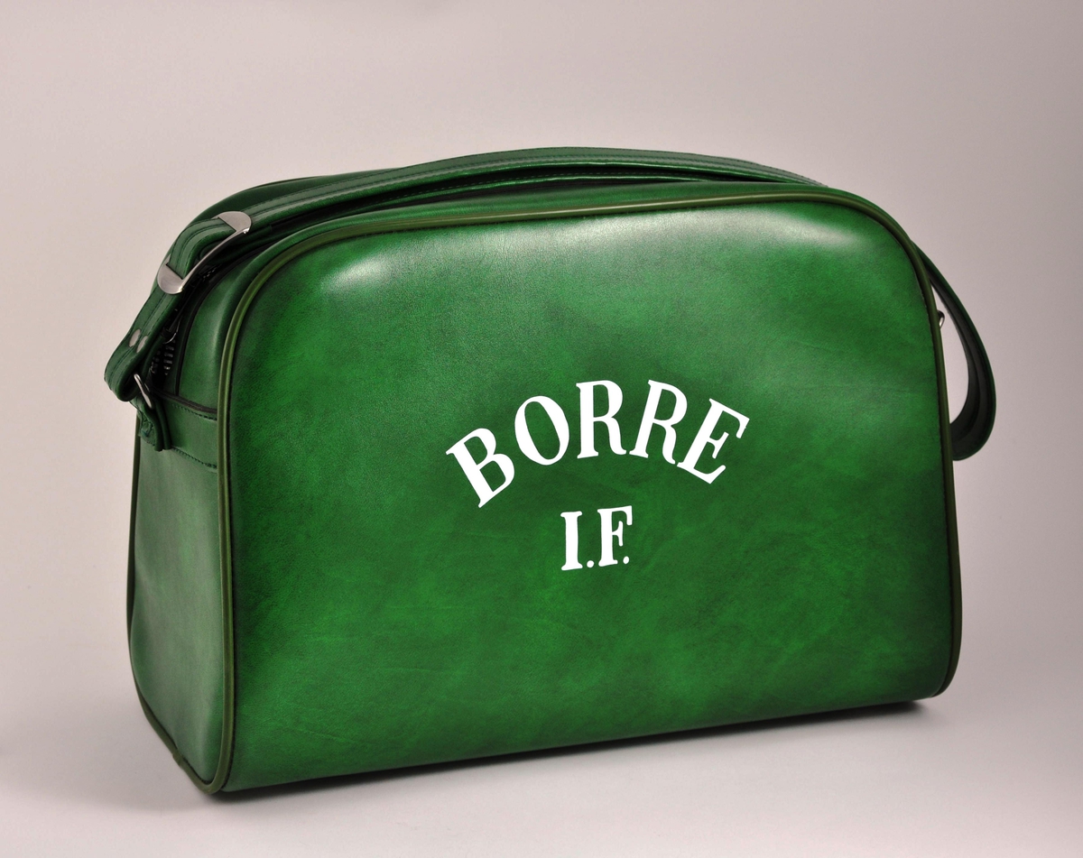 Bag i grønn plast med glidelås og regulerbar skulderrem.