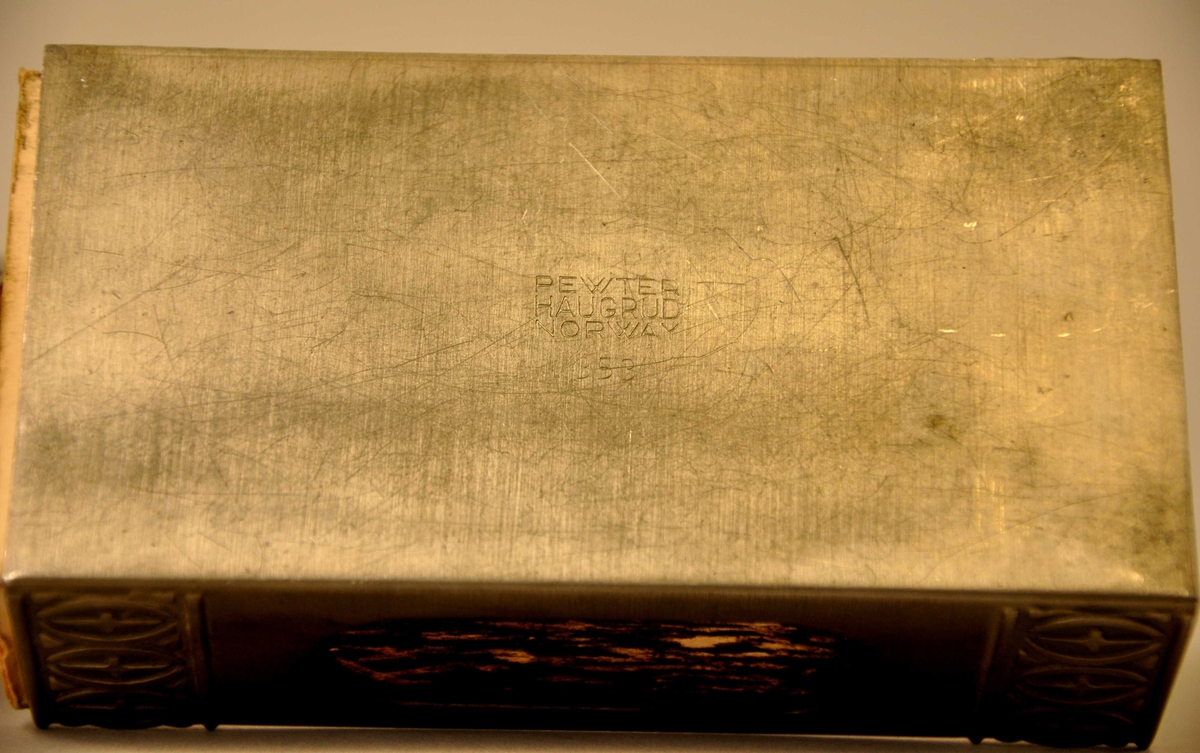 Dekorbord med tettståande, opne elipser med ein kross inni. Mønsteret går over 3 sider fyrstikkøskjeholdaren i kvar ende. 