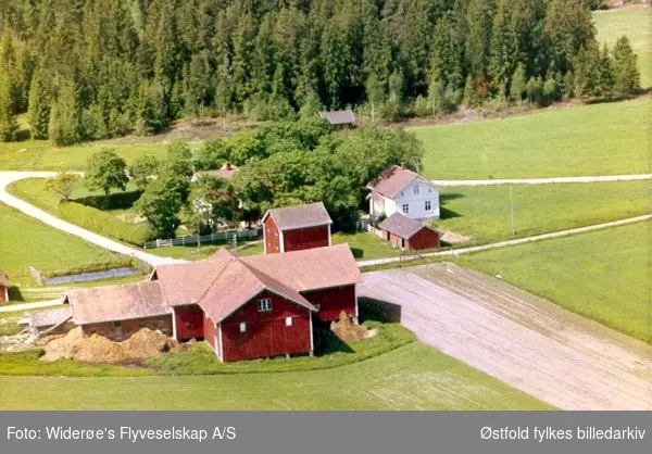 Skråfoto av gården Ås i Rakkestad, 13. juni 1964.
Daværende eiere var Inger Bordewick og Åse Børsting.

Gården var forpaktet bort til Kristian Trinborg.