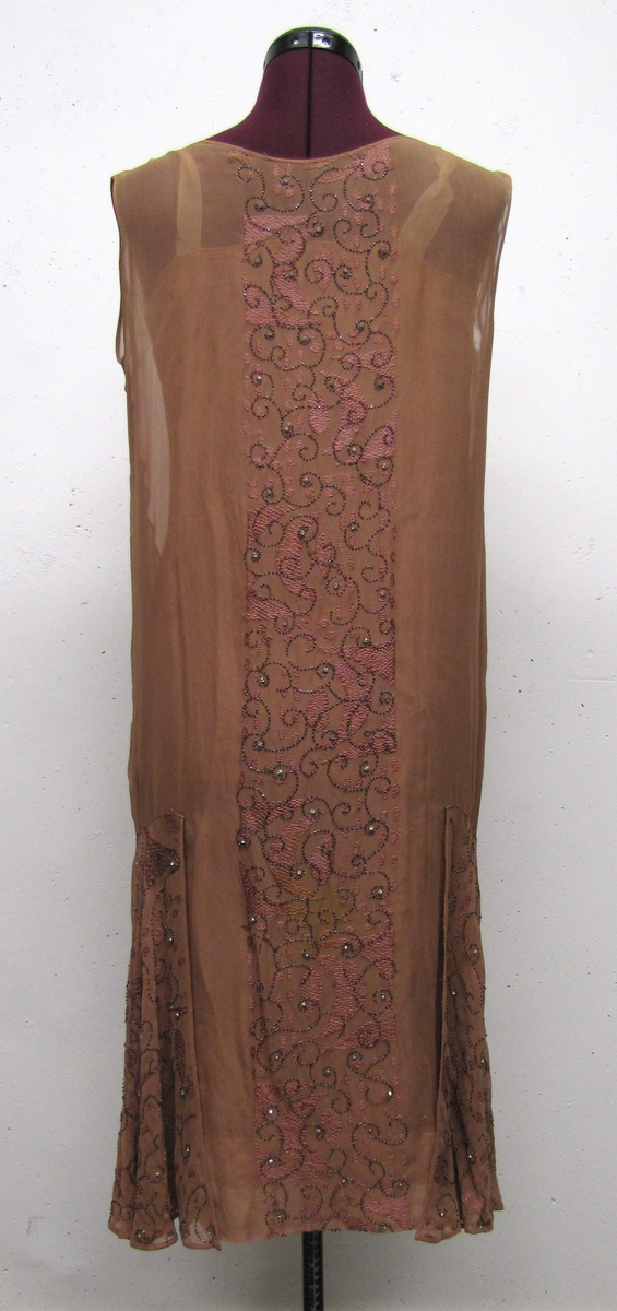 En rosa klänning (Smokingklänning), ärmlös med lågt skuren midja. Pärlbroderier.

Klänningen är från 1920-talet.