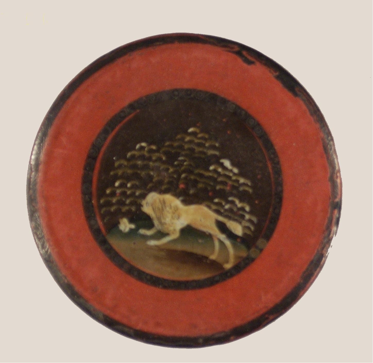 Nipperask lackerad i rött och svart, på locket lejonfigur (pudel?). På undersidan med vit färg 3.