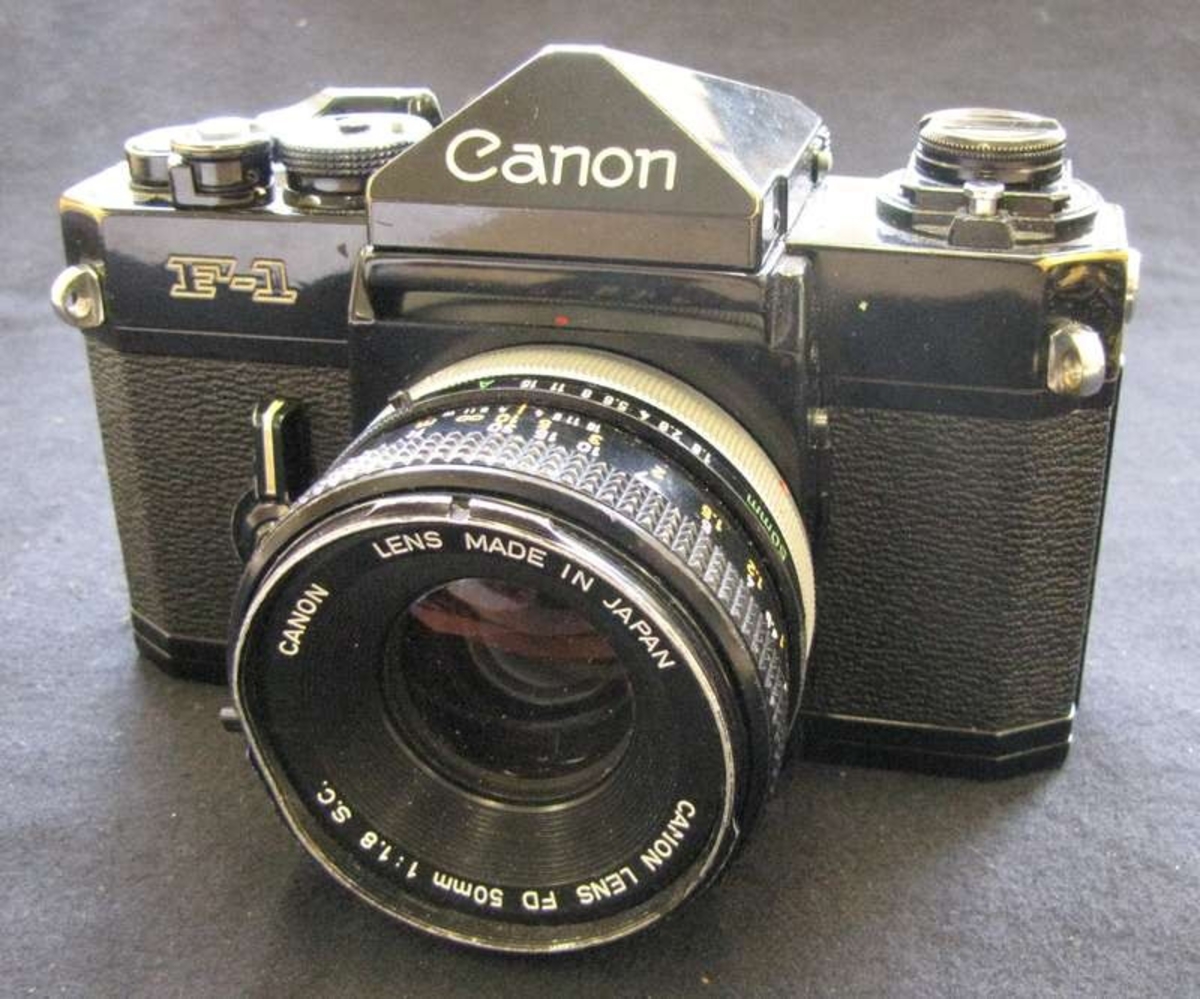 Kamera. . Till kameran finns objektivet Canon lens fd 50mm, 1:1,8, Nr 825774.

Kameran köptes in för att behovet av kameror ökade i och med byggnadsinventeringar ökade under 1970-talet. Detta är en av de två Canon F-1 som köptes in ca 1975. P g a tekniskt fel användes inte denna kamera mer än fram till ca år 2000.

Kameran köptes in 1975 men införlivades med samlingarna 2011.