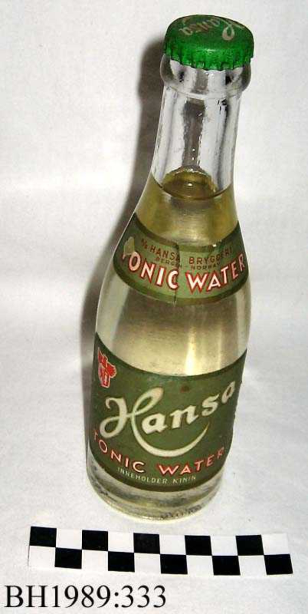 Brusflaske i klart glass, med grønn metallkapsel merket Hansa.