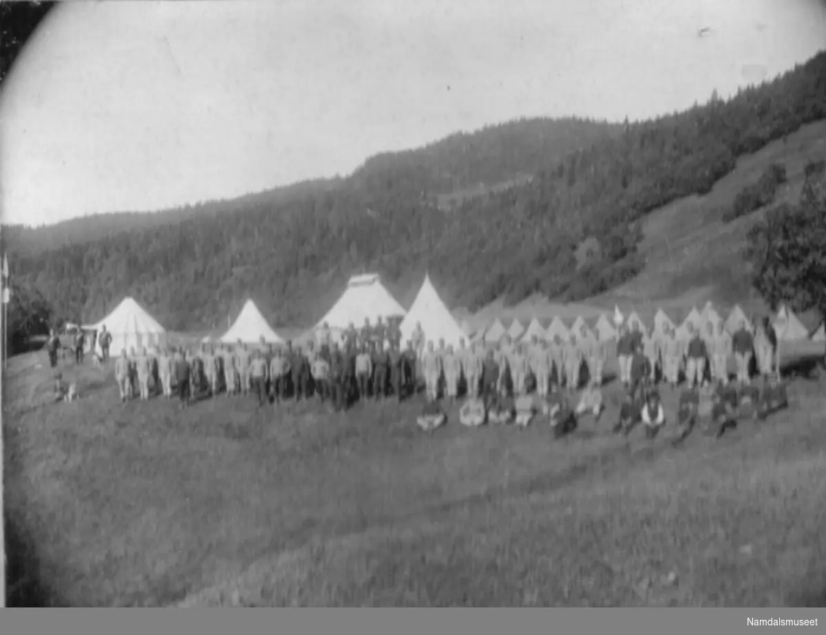 Militærøvelse. Soldater oppstilt foran en teltleir.