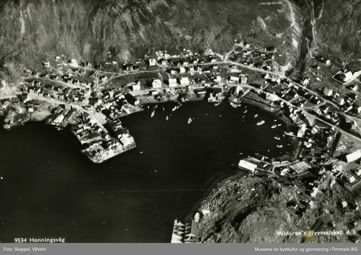 Postkort. Flyfoto av Honningsvåg, med bebyggelsen og indre havn. August 1936.