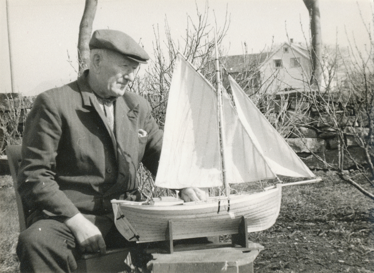 Nils O. Synnes sitt ved siden av dekksbåt- modellen han har laga. Dette var den første vellykka dekksbåten for både segl og årer.