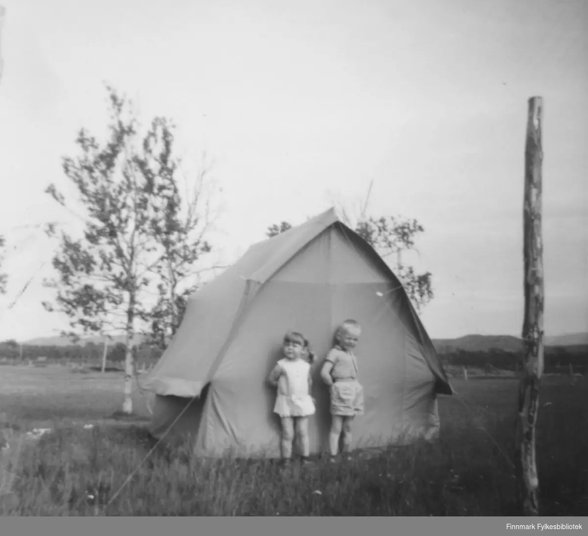 To barn står utenfor et telt. Sted og personer er ukjent.