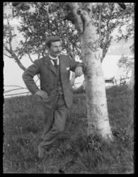 Mann lener seg mot bjørketre med hjerte i barken