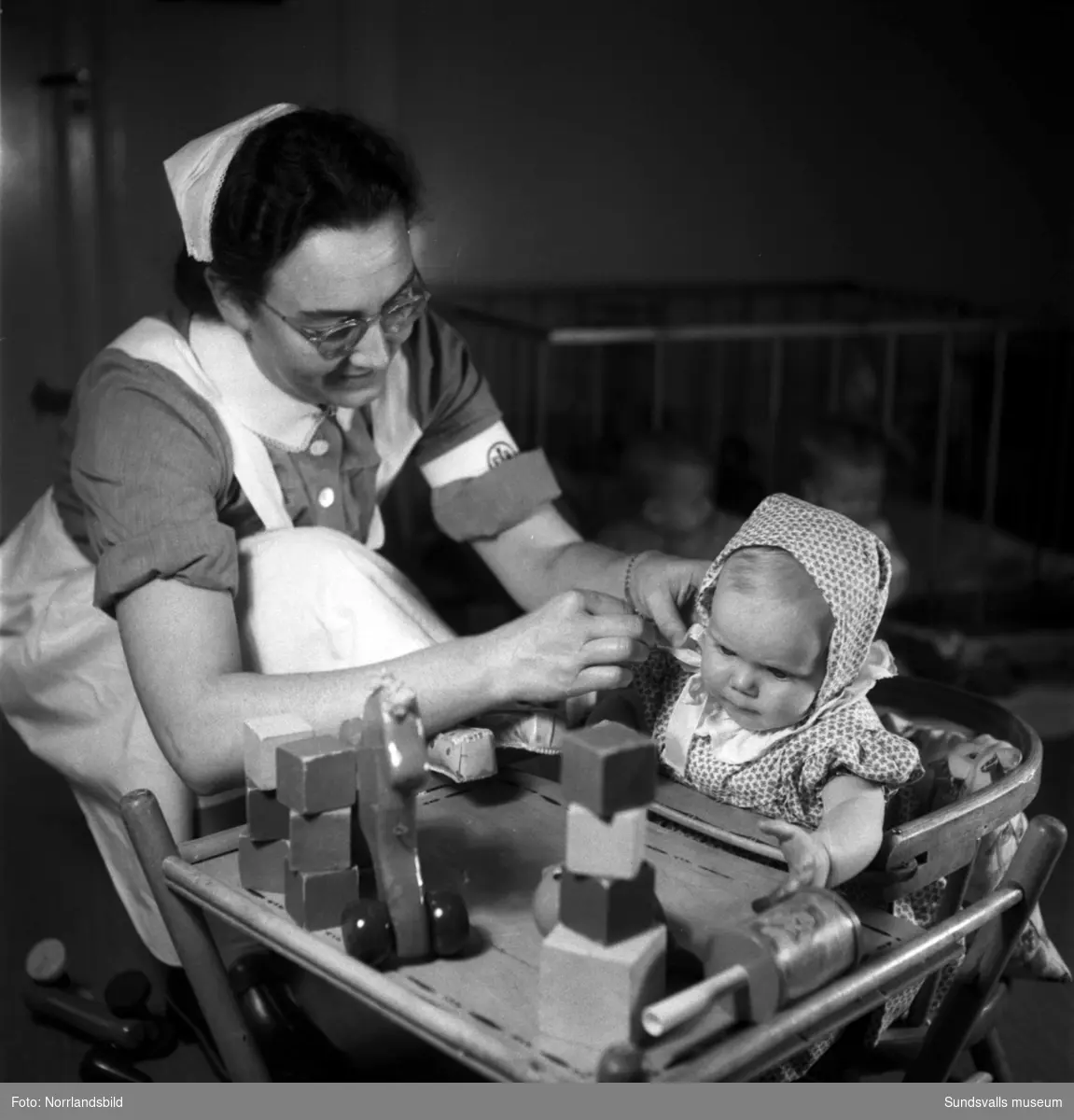 En serie bilder från verksamheten på Vita Bandets spädbarnshem, fotograferat för en informationsbroschyr. På bild två ses föreståndaren (för spädbarnshemmet) Anna Lilja till höger samt rektor (för barnsköterske- och husmodersskolan) Elsa Rutbäck till vänster.