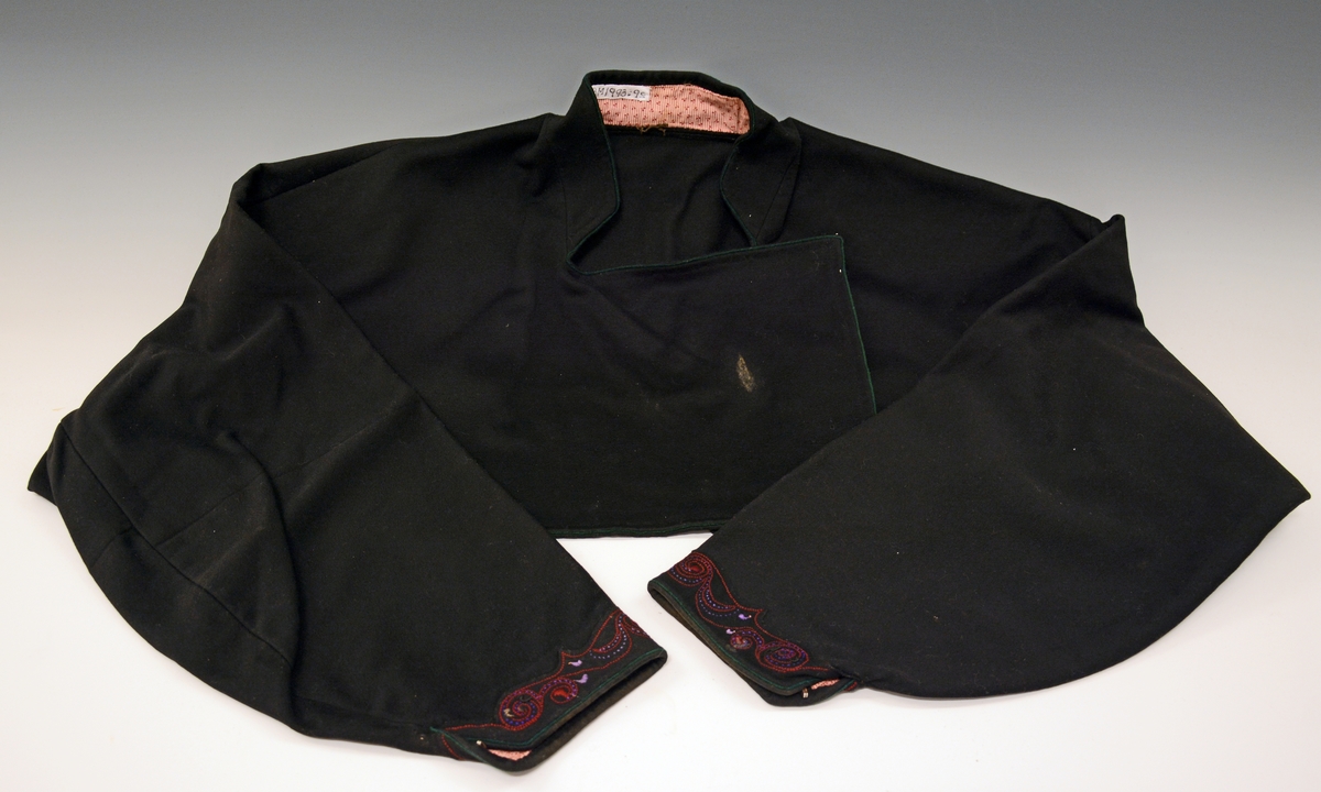 Drakten består av stakk, forkle, 2 trøyer, 2 brikkevevde belter, TGM-BM. 1993:009.A-E.
Kvinnetrøyen er av svart klede.Grønn tittekant langs kragen, framslaget og ermsplitten. Rundt ermene nederst er det applikasjon med hånsydde rosestikninger i rødt og lilla. Ryggstykket ender i en "klokke" nederst. 2 stk metallhekter under framslaget (en del mangler), 1 stk metallhekte på hver ermsplitt. Innvendig er trøyen delvis fòret med småmønstret bomullstøy.
