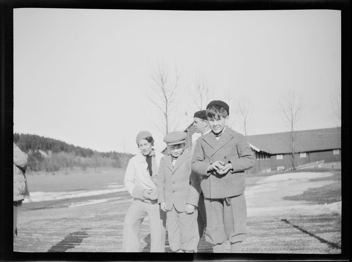 Celina Marie Mathiesen, en mann og to gutter har stilt seg opp for fotografen på gårdsplassen på Linderud gård. Den fremste gutten holder en snøball i hånden.