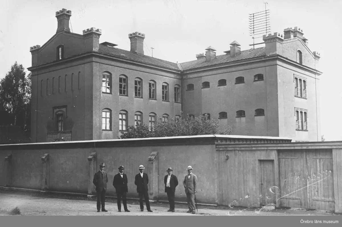 Fängelset, grupp fem män framför byggnaden.