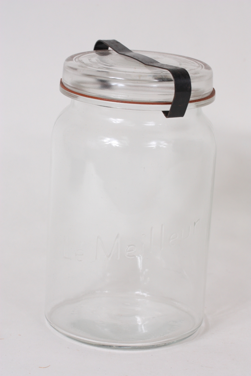 Sylindrisk glas med lok som blir halde på plass med ei metallklemme