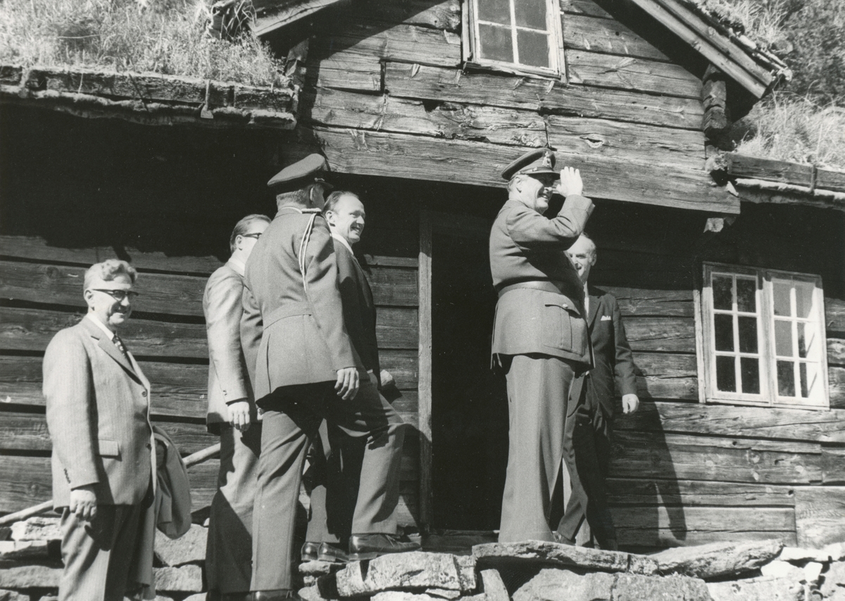Kong Olav V hilser folket på trappa utenfor Strandastova. Tidspunktet er fra Syndmøre Practiske Landhuusholdningsselskab sitt 200 års jubileum på Sunnmøre Museum 1973.