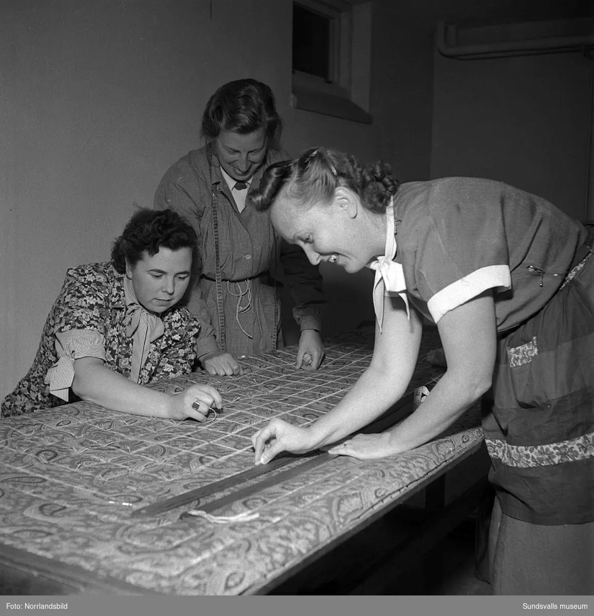 Tre kvinnor som går en kurs i madrasstoppning.
