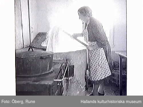Klädvård. Tvättning av kläder i gårdens brygghus. Tvätten kokades i en stor gryta och tvättades i den handdrivna tvättmaskinen i förgrunden. Först kokades vittvätten, sist skurades trasmattorna. El-driven tvättmaskin köptes på slutet av 1950-talet. På bild 9-10 manglar Maria.