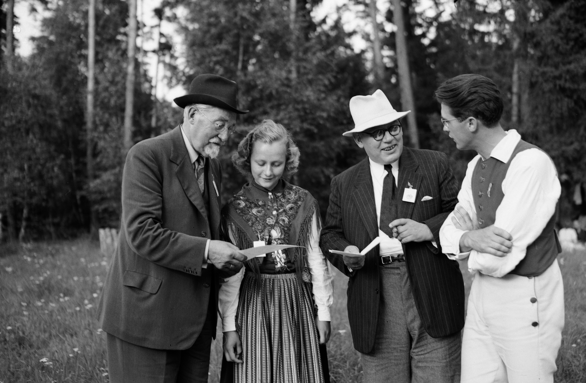 Ung kvinna och män vid spelmanstävling i Granebergsparken, Sunnersta, Uppsala augusti 1945