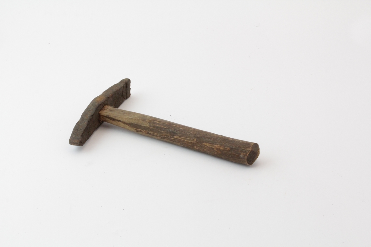 Hammer med treskaft (skaftet er rett og har avrundet tverrsnitt). Hammerhodet er smidd i jern;  med rektangulær bane og tverrstilt penn.
