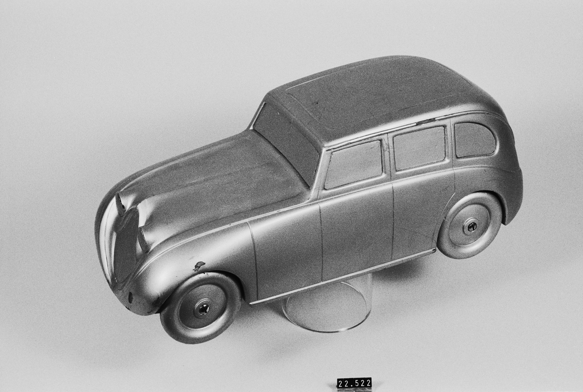 Trämodell i skala 1:10 som visar ett tänkt utförande av den bil som byggdes 1933. Skulpterad ur ett limmat träblock, med svarvade trähjul. Modellen omlackerad ett antal gånger för att prova olika färgsättningar.