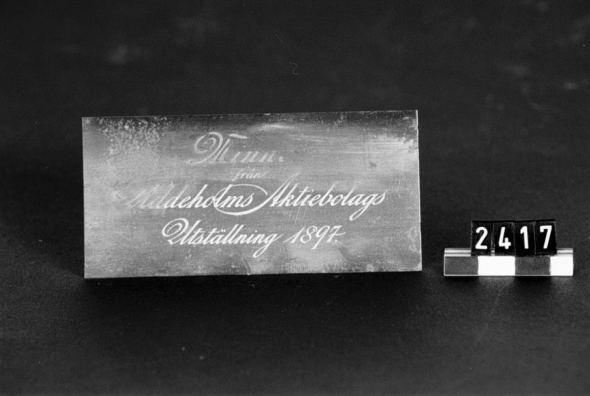 Reklamkort, etsat på tunn stålplåt. Märkt: "Minne från Uddeholms Aktiebolags Utställning 1897".