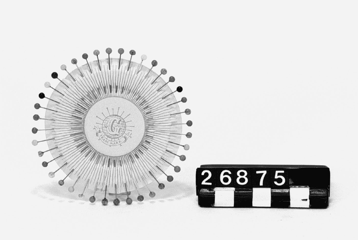 40 st. knappnålar med huvuden av färgat glas i tolv färger. Nålbrevet märkt "G" samt "Trade Mark".