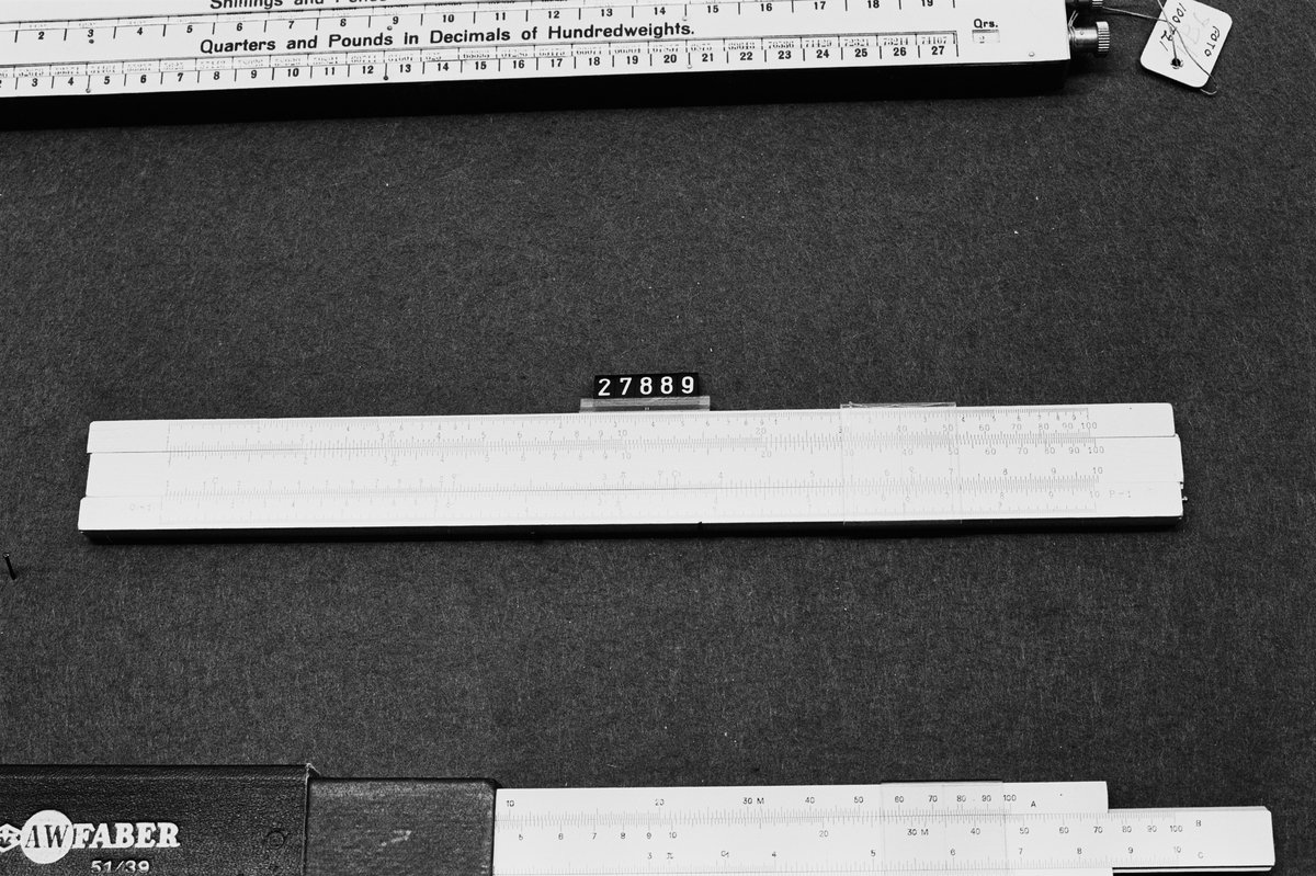 Räknesticka typ nr. 8, med tre logaritmiska skalor, system Rietz, för 1-1000, 1-100 och 1-10 samt engelska tum i 50-delar, på vit lack på trä, i fodral av papp. Tabell med konstanter.