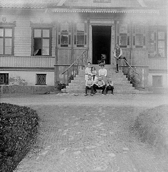Kvinnor och barn samlade för fotografering på verandans trappa.