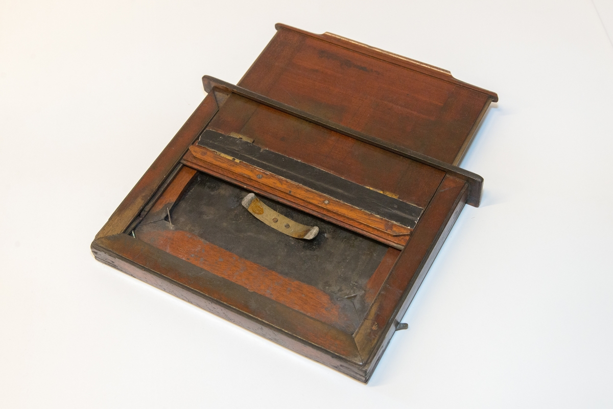 Gruppering med fotokamera i oppbevaringskasse, separat metall-lokk, stereolinse, lause delar som negativplate, mattskive, blendarsett og diverse smådelar.