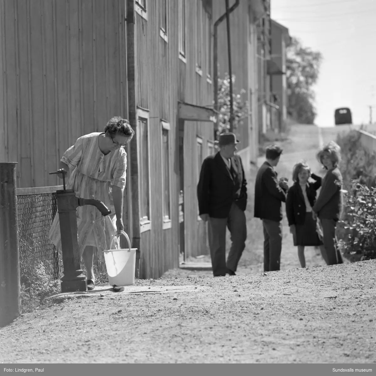 Kvinna hämtar vatten vid gårdspumpen på Bleckslagaregatan 34. Det närmaste huset revs under 1960-talets början.