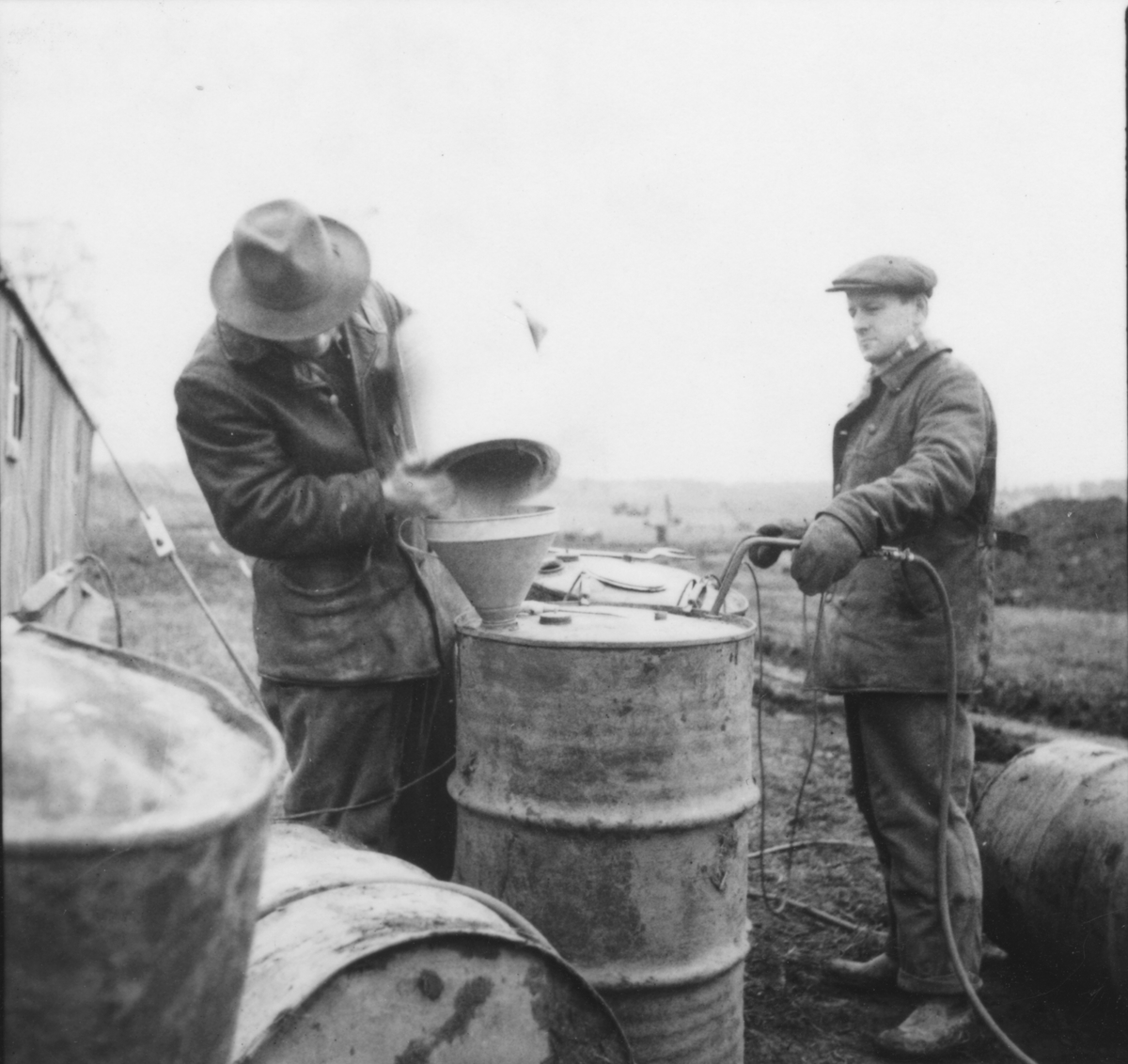 Blandning av bränsle till flygbomb, 1940-tal.
Två män i arbete vid ett fat.